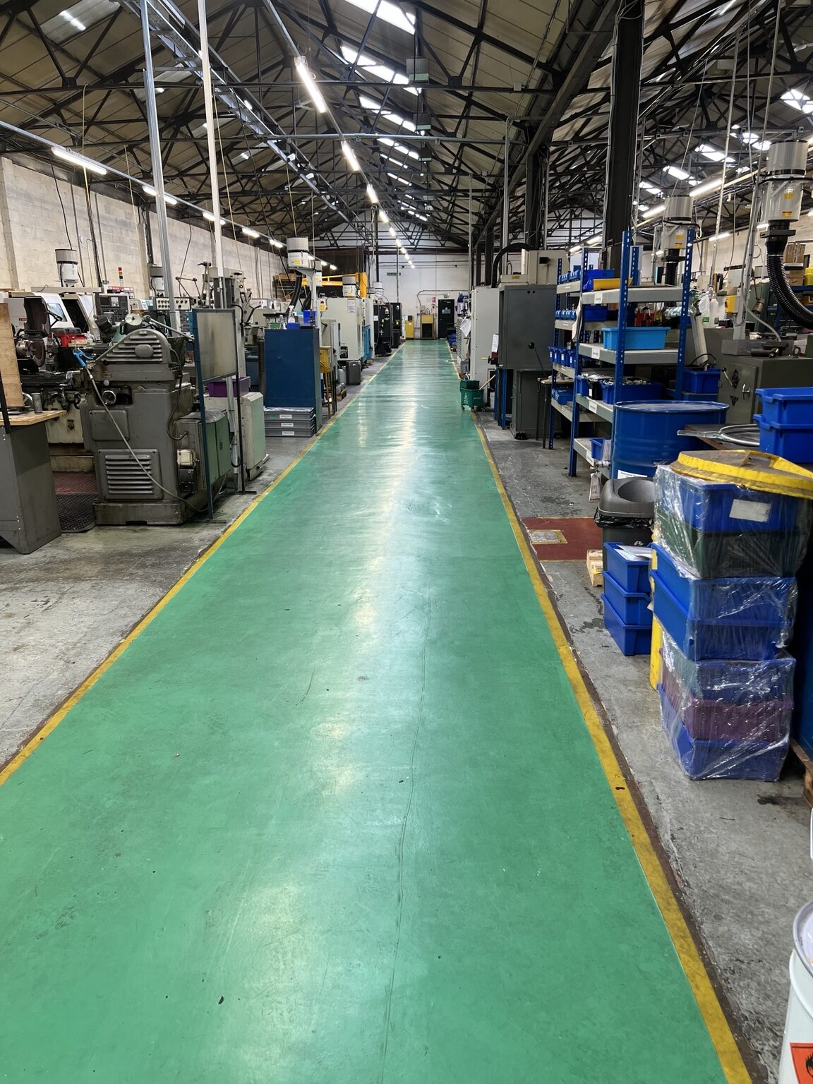 Long green resin walkway through a working factory